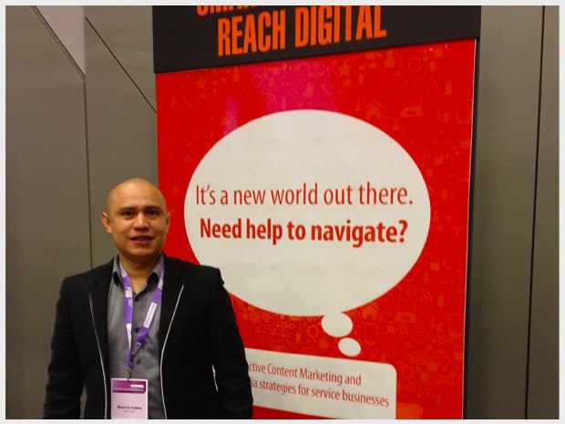 Reach Digital director Mauricio Iraheta standing beside an exhibition banner reading It's a new world out there, need help to navigate?